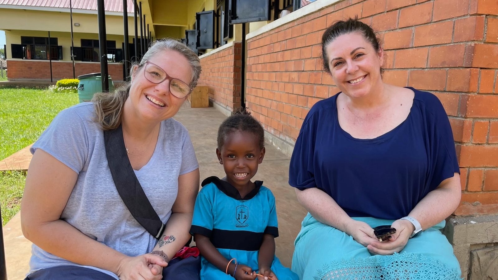 Two visitors with a Nursery School student at the New Life campus in Bulesa, Uganda